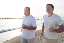 Two men running along the coast in bright sunlight