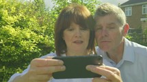 Active senior caucasian couple pulling funny faces taking selfies on a smartphone