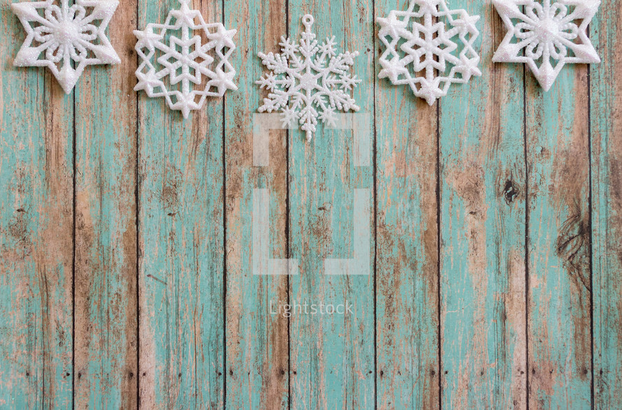 snowflake ornaments on a green wood background 