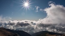 Fast clouds in blue sky with sun shine in beautiful mountains nature Time lapse
