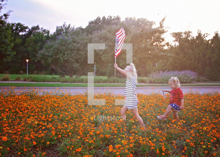children marching through a field of orange flowers holding an American flag 