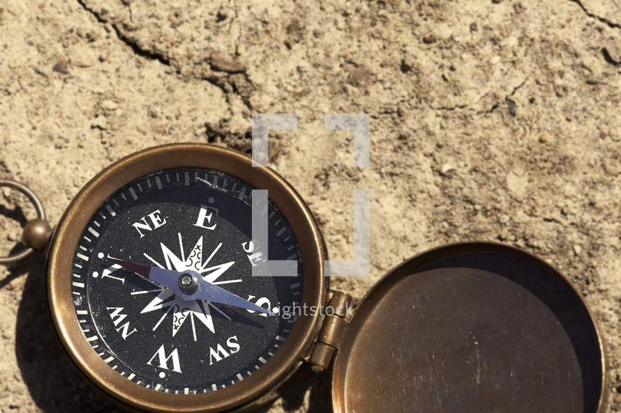 An open compass on bare earth.