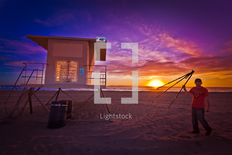 lifeguard stand at sunset and a man with a tripod