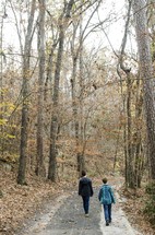 brothers walking down a path in a forest in fall 