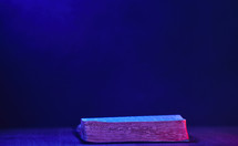 Bible open against a dark background with blue and red light
