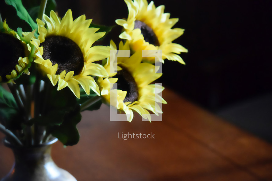 vase of sunflowers on a wooden table 