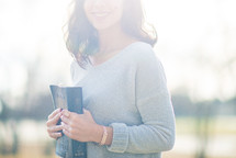 a young woman holding a Bible against her chest 