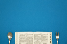 an open Bible with fork and spoon 