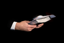 Hands holding a Bible and sermon notes.