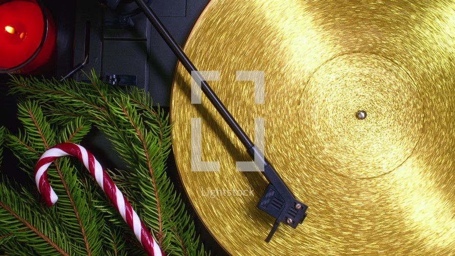 Fortuna gold, movie of retro-styled record player spinning golden vinyl. Cinemagraph. Christmas concept - spruce branch, lollipop and candle. Analog audio equipment, sound concept. High quality photo