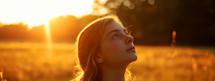 Portrait of a beautiful girl meditating in the field at sunset.	