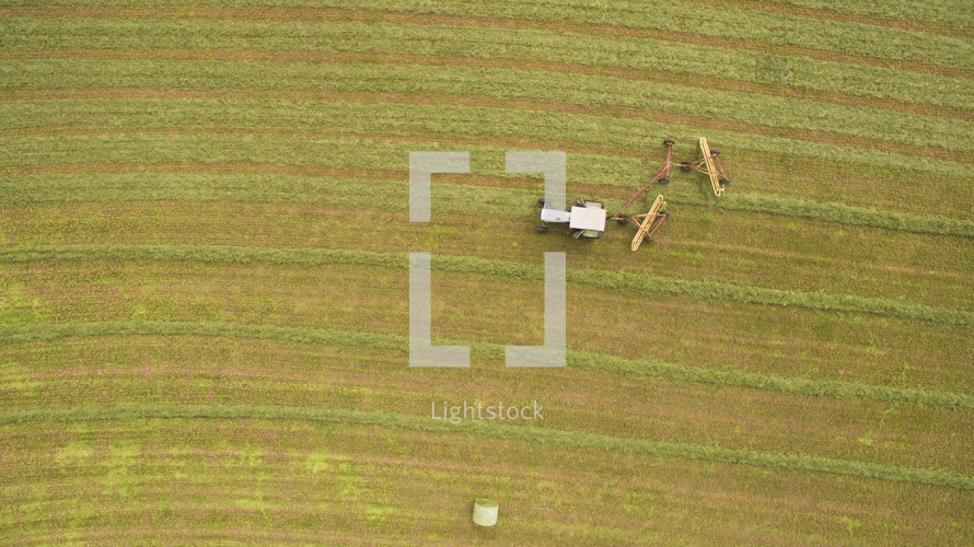 An aerial view of a field being harvested by a combine.