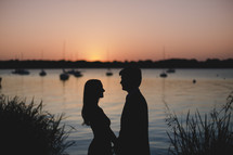 silhouette of a couple in love and distant boats on the water