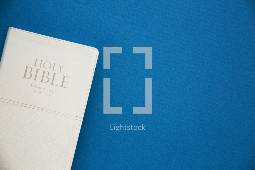 a Holy Bible with a white cover on a blue background.