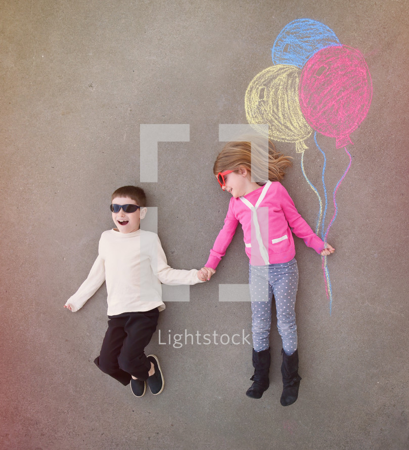 brother and sister holding sidewalk chalk balloons 