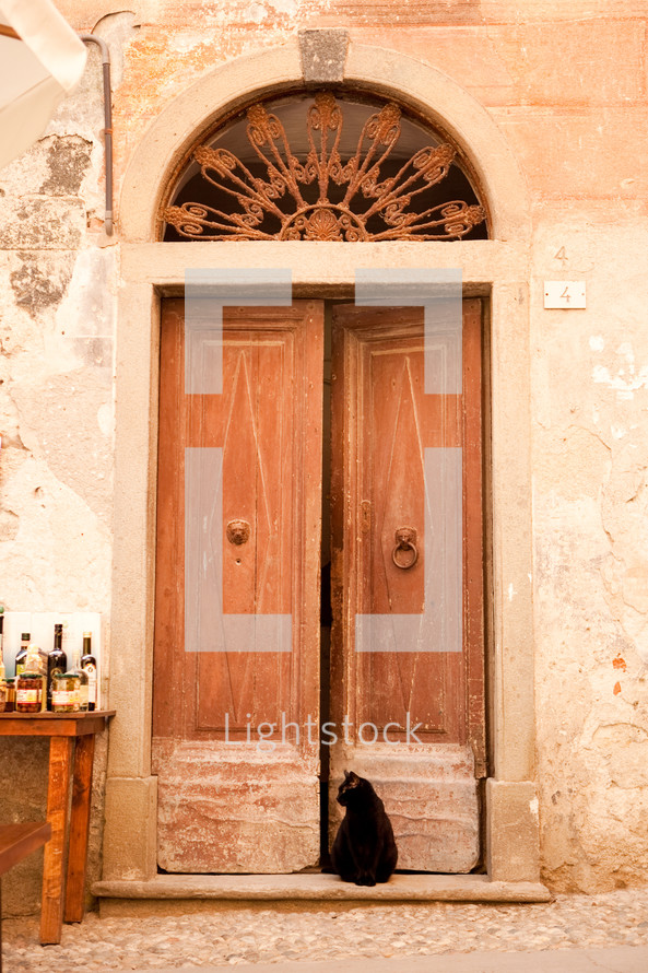 Black cat sitting in an old Italian doorway