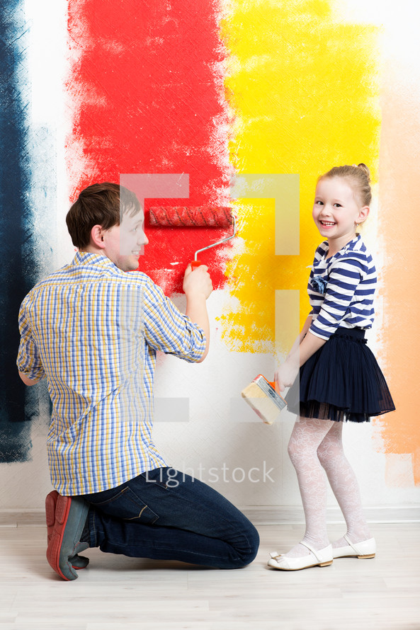 Happy girl painting wall with father