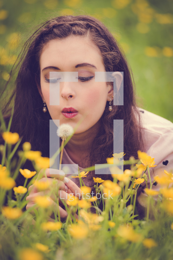 a teen girl blowing a dandelion 
