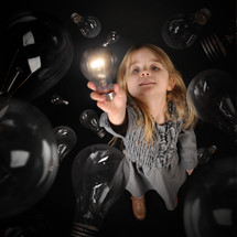 a girl holding up a bright lightbulb 