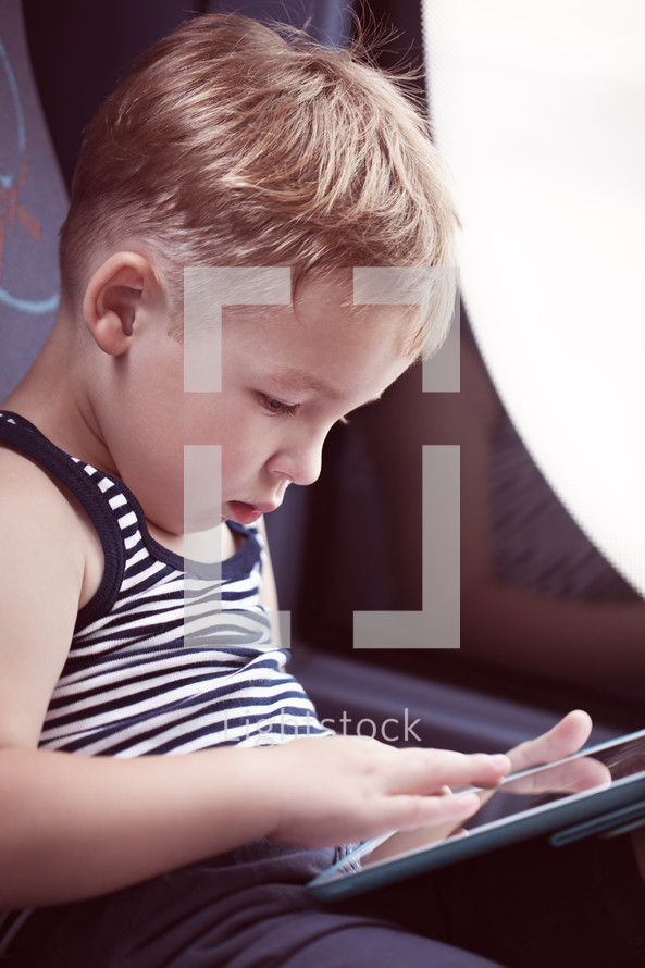 Little child using touch pad while traveling by bus