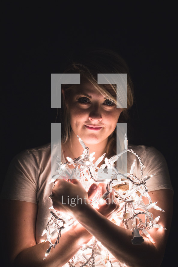 face, eyes, woman, holding, string of lights, Christmas lights, light 