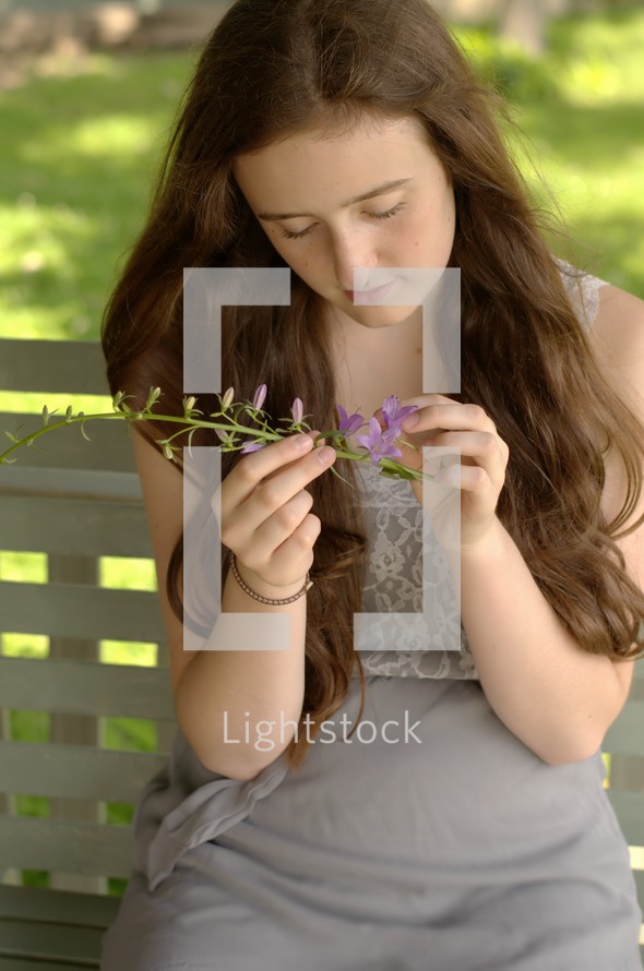 woman looking at a purple wildflower 