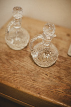 Two glass bottles resting on a wooden table