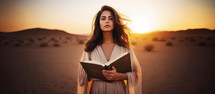 Woman holding a bible in a desert. Worship