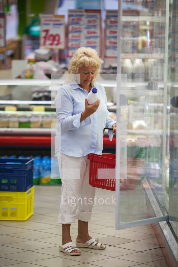 Woman taking milk from the fridge in supermarket