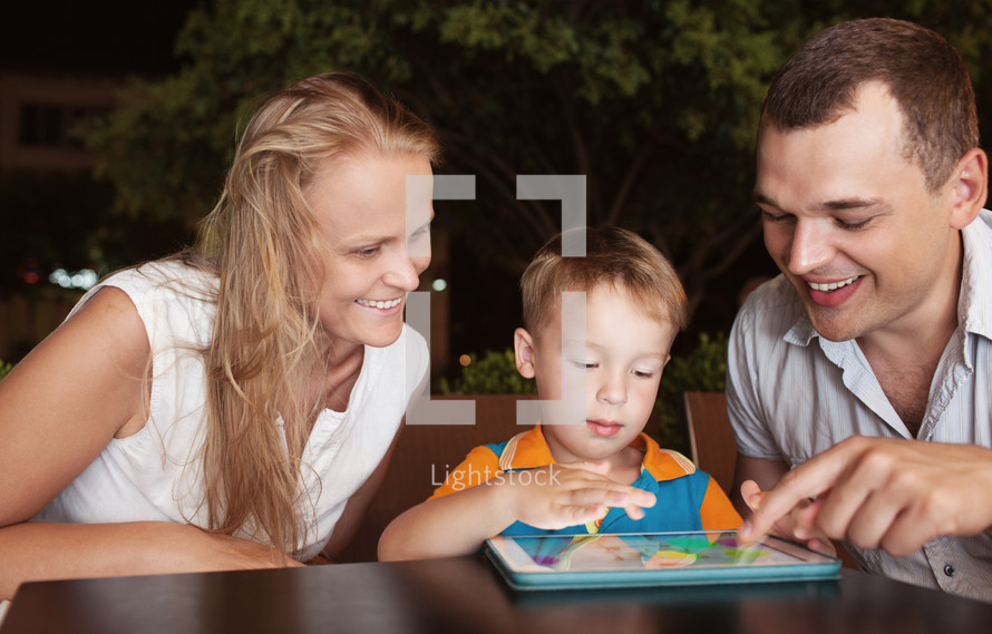 Family of three spending time in cafe with tablet computer