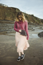 a woman in a skirt walking on a beach 
