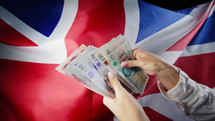 UK flag background. Woman counting GBP money pounds sterling.