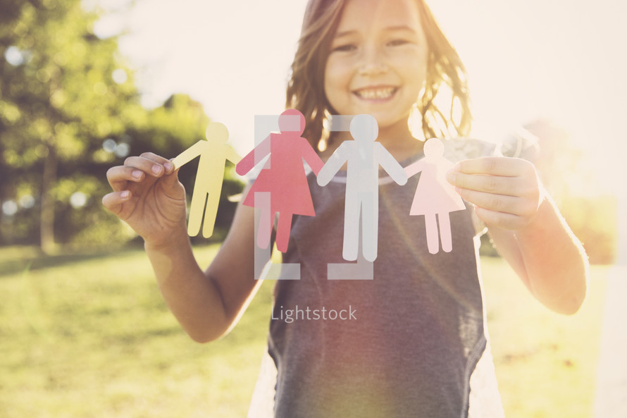 a girl child holding paper dolls 