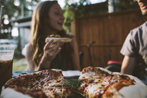 A woman eating pizza outdoors. 