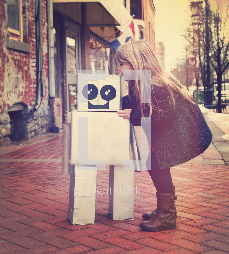 a girl playing with a cardboard robot 