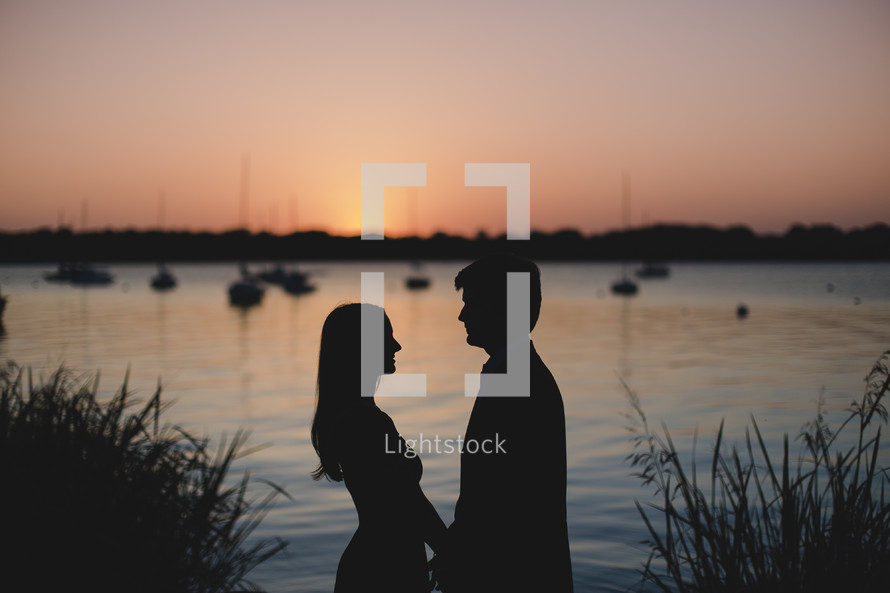 silhouette of a couple in love and distant boats on the water