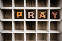 word Pray on a wood shelf 