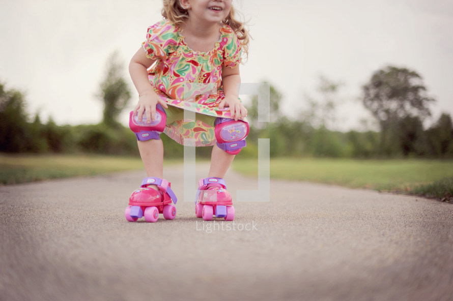 child in roller skates and knee pads 