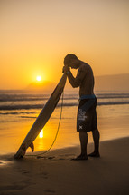 surfer with his head bowed in prayer