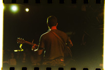 a man on stage playing a guitar on a filmstrip 