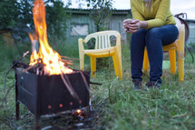 Woman with tea near the fire in yard