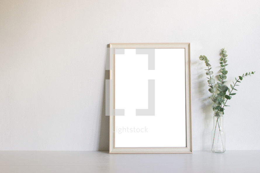 blank frame, and vase with eucalyptus 