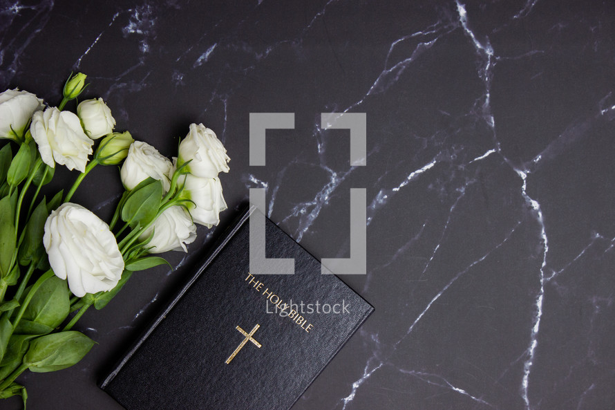 Bible on a black marble desk with white roses 