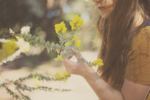a young woman smells the fresh blossoms on a tree