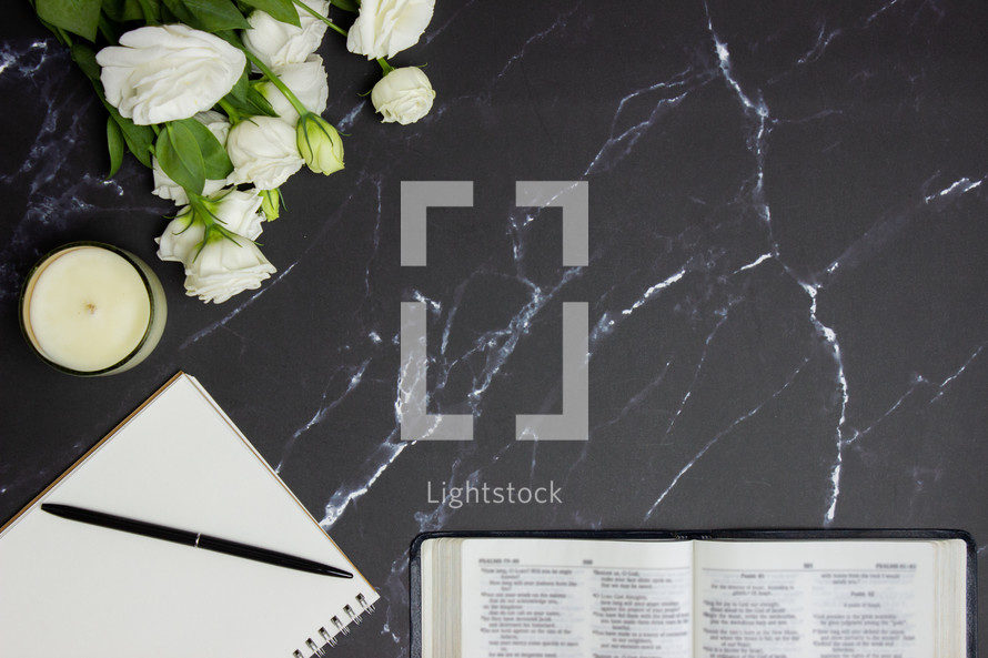 open Bible on a black marble desk with white roses 