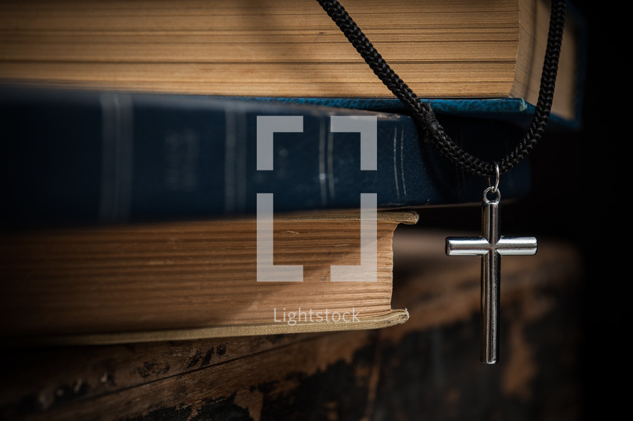 cross necklace and stack of books 