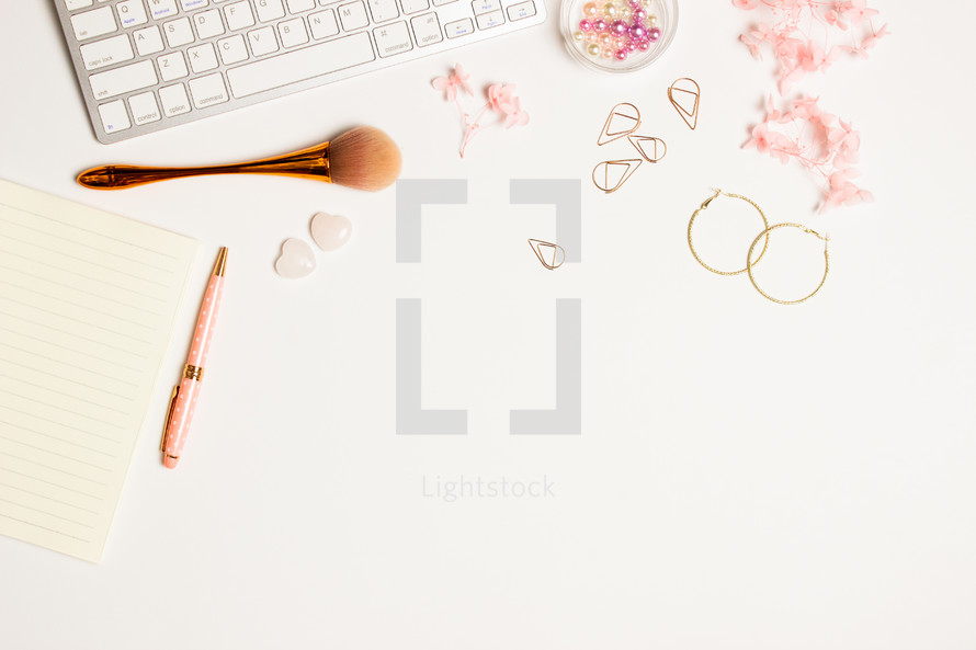 Women working space with make up blush, pink flowers, earrings over white background. 