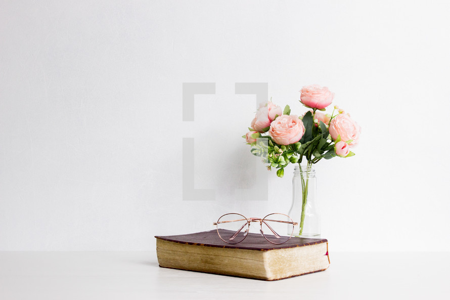 vase of flowers Bible, reading glasses on a white background 