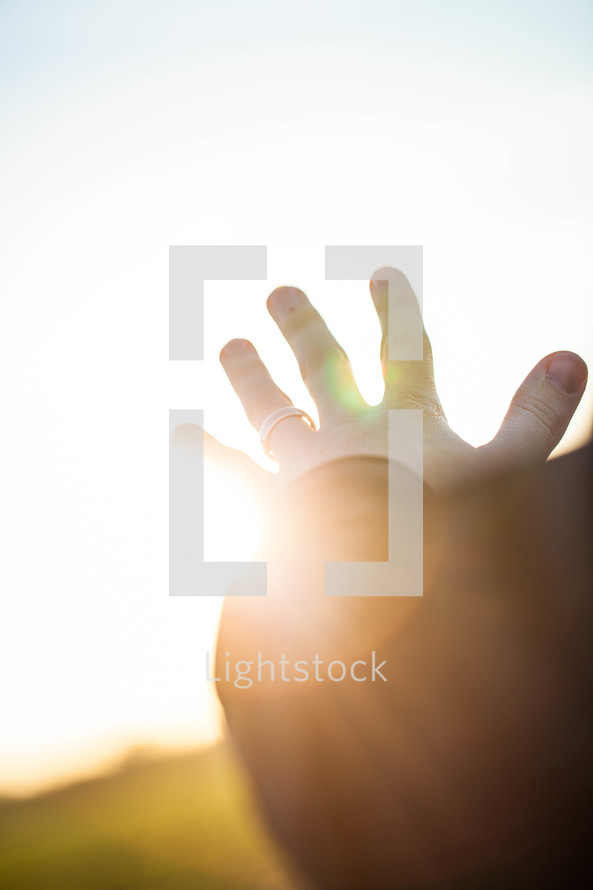 hand reaching out to God glowing in sunlight