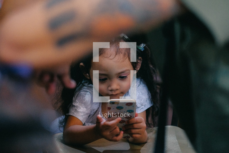 a little girl looking at an smartphone screen 